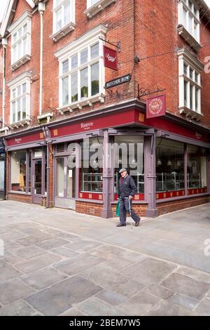 Elderly man walking past a bakers shop closed due to Coronavirus emergency Stock Photo