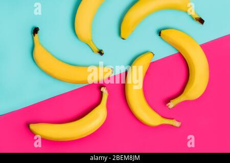 Colorful fruit pattern of fresh yellow bananas on pink and pastel blue background. From top view Stock Photo