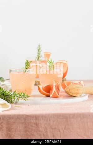 Grapefruit juice with rosemary in glasses on the table. Refreshing summer cocktail. Stock Photo