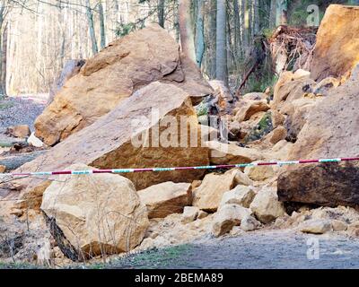 Area marked with police tape, do not entry. Collapsed rocky boulders faal down from slope and blocked forest path. Danger place Stock Photo