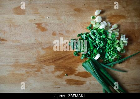 Shallow depth of field (selective focus) image with chopped spring onions on a wooden cutter. Stock Photo