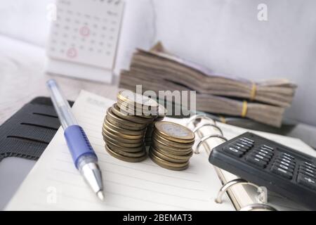 stack of coins, cash and calculator on notepad. Stock Photo