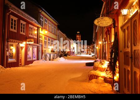Cosy evening mood in the Kjerkgata by night in the historical mining town of Røros in wintertime, Norway Stock Photo