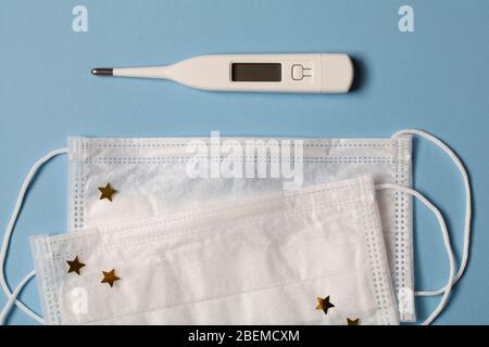 Medical mask with decoration for protection against coronavirus. protective mask and thermometer for measuring temperature on blue backbround. Medical Stock Photo