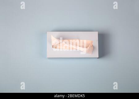 Picking facial napkin, tissue paper from the tissue box on blue background. Top view. Flu, illness, pandemic concept Stock Photo