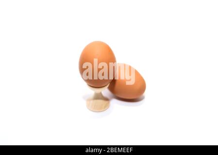 Two brown chicken eggs isolated on the white background. One is in holder. Stock Photo