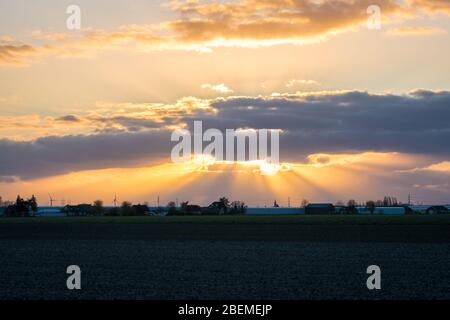 Sunset with beautiful colored sun rays or crepuscular rays over the landscape of Holland Stock Photo