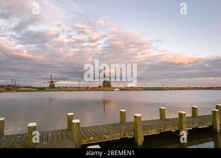 Windmills at the shore of lake 'Rottemeren', Holland under a beautiful evening sky Stock Photo