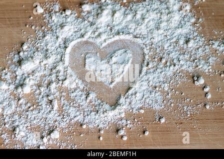 White flour on a wooden table with heart symbol, ready for cooking and dough preparation Stock Photo