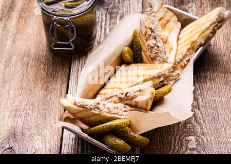 Homemade tuna sandwiches with cheese served with pickles on rustic wooden table Stock Photo