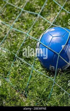 Football in the back of a goal net Stock Photo