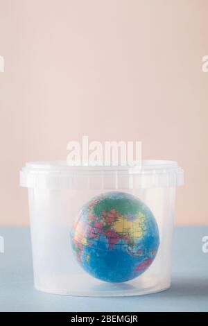 Earth in plastic disposable box on blue and pink background. Concept pollution of environment with plastic waste, ecological problems. Stop plastic po Stock Photo