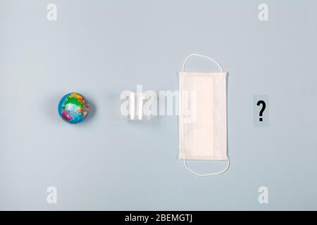 Earth, plastic disposable box, medical mask and question mark on blue background. concept what is next. plastic pollution, struggle with corona virus. Stock Photo