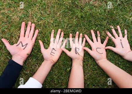 Word merci written on child hands Stock Photo