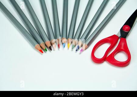Scissors and colored pencils on a white background Stock Photo