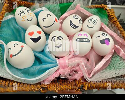 Easter eggs in a basket with painted faces and hearts instead of eyes Stock Photo