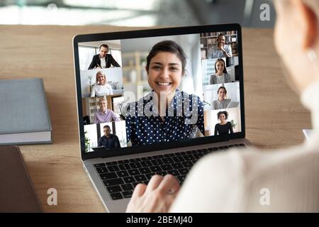 Laptop screen over woman shoulder view during group online communication Stock Photo