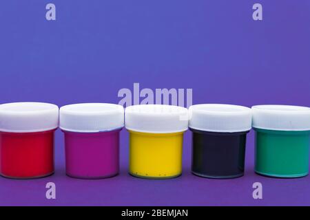 Large set of acrylic paint cans in a row. Colorful paints neon blue and violet background with copyspace Stock Photo