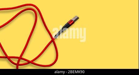 USB cable on an orange background. A wire for smartphones, charging and a connecting device for a computer. Top view, copy space Stock Photo