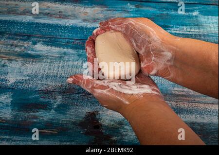 Someone is soaping their hands with a piece of toilet soap on a wooden background. Close up. Regular hand washing with soap is a prevention of COVID-1 Stock Photo