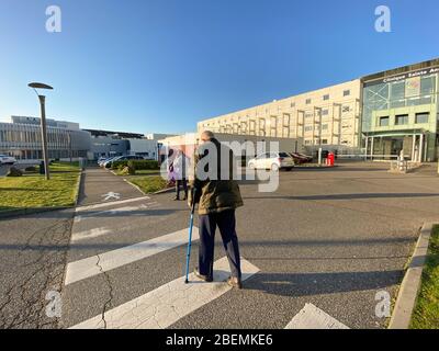 Strasbourg, France - Jan 20, 2020: Side view of patients senior man with two walking canes in front of French hospital in Strasbourg Sainte Anne Stock Photo