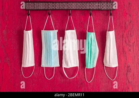 Medical masks hanging on hanger for family due to coronavirus protection covid-19 on red background Stock Photo