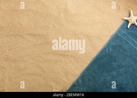 Summer vacation composition. Towel with seashell on sand background Stock Photo