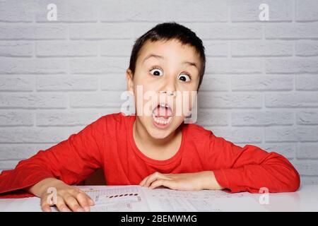 Upset boring schoolboy doing homework. Child tired of doing homework studying with pen on open books. overloaded child. Back to school. distance learn Stock Photo