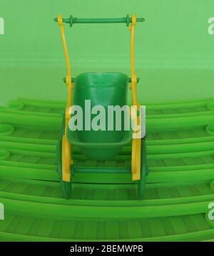 empty green plastic toy baby pushchair (aka stroller) Stock Photo