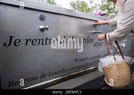 Pilgrim collecting holy water from faucets at the sanctuary in Lourdes, France, Europe Stock Photo