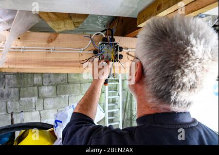 British welsh male wiring a junction box at home doing diy in garage Stock Photo