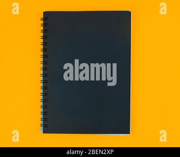 A diary of black color cover placed on an isolated orange color paper background Stock Photo