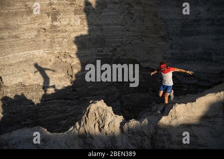 One man trail running down through a ridge on a sandy terrain Stock Photo