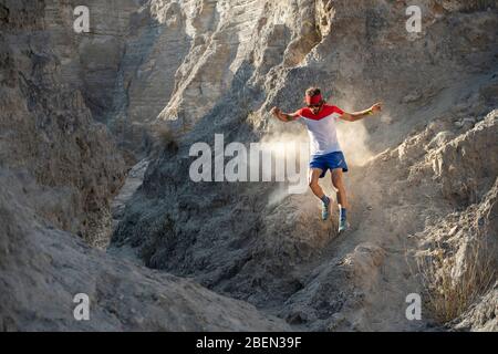 A man trail running down on technical terrain leaving dust on his way Stock Photo