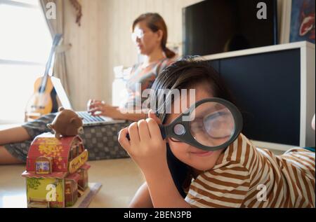 A girl is playing nearby a mother who is working with a laptop Stock Photo