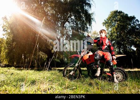12 year old boy having a break on his off road motorbike Stock Photo