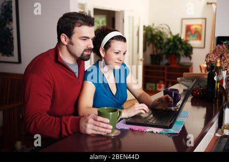 Couple work on laptop computer at home Stock Photo