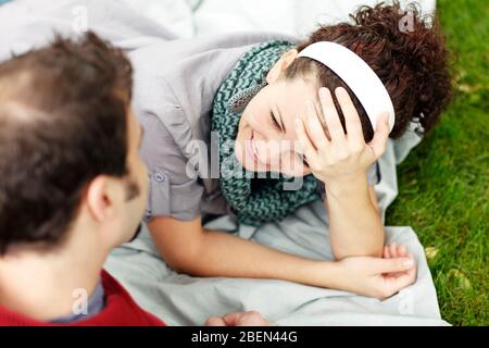 Woman smiling at her partner while laying on blanket in the gras Stock Photo