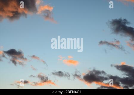 Close-up of orange and  dark  clouds   after   rain and storm  at sunset against blue sky . Stock Photo