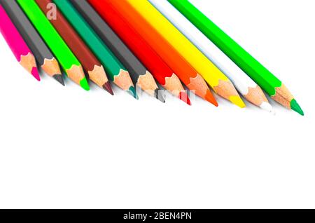 Row of different colored pencil crayon placed on top of an empty bright white colored paper background Stock Photo