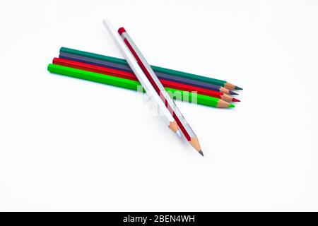 Two different colored wood pencil crayon placed on top of four pencil crayons on a white empty paper background Stock Photo