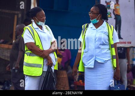 Two medical service workers chat while waiting for transport at a bus stop in Lagos, Nigeria. Stock Photo