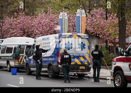 Brooklyn, United States. 14th Apr, 2020. EMS workers clean and disinfect their ambulance outside Brooklyn hospital amid the coronavirus outbreak in NY. As the curve flattens, New York continues to see high daily death tolls, recording once again over 700 coronavirus deaths yesterday. Credit: SOPA Images Limited/Alamy Live News Stock Photo