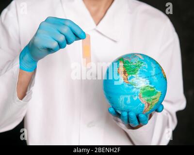 Hands in white gloves holding a globe, an adhesive patch in Usa. Stock Photo