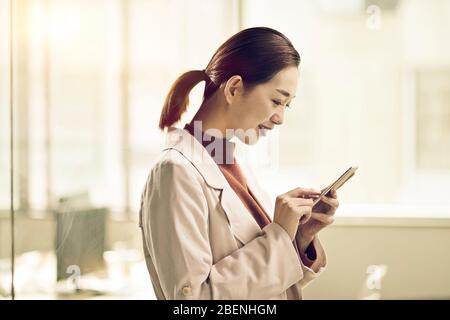 young asian business woman entrepreneur checking or sending text messages using mobile phone Stock Photo