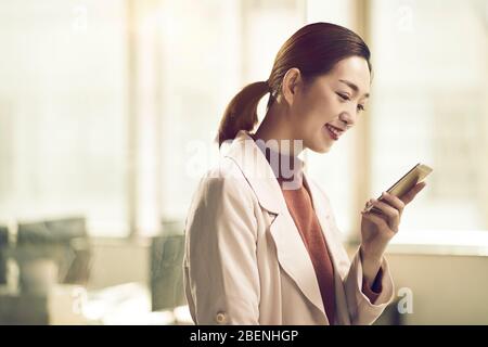 young asian business woman entrepreneur checking text messages using mobile phone Stock Photo