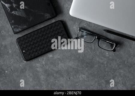 smartphone on office desk with laptop and cup of coffee on gray concrete. Business or education concept. Top view with copy space, flat lay Stock Photo
