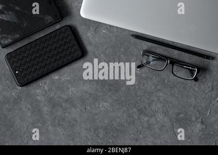 smartphone on office desk with laptop and cup of coffee on gray concrete. Business or education concept. Top view with copy space, flat lay Stock Photo