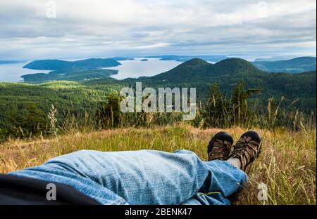 A first person view of a man relaxing on a hillside enjoying a spectacular view of the San Juan Islands. Stock Photo