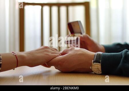 Closeup of man holding engagement ring and woman's hand Stock Photo